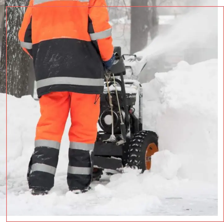 Employé au souffleur à neige dégageant un trottoir